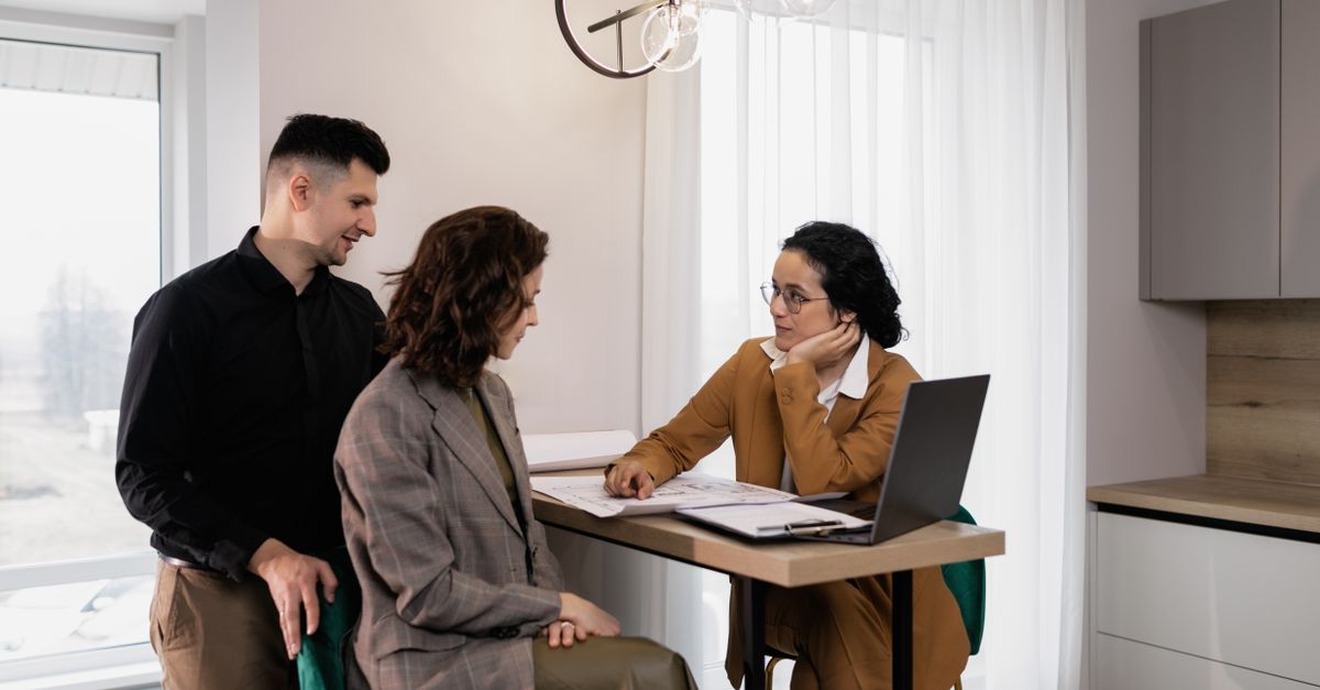 A couple discussing a property with a real-estate agent over a laptop.